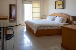 a bedroom with a bed and a glass table at Mansouri Mansions Hotel in Manama