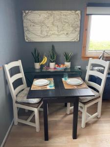 a dining room table with two chairs and a black table with two plates at Music of the Sea- Isle of South Uist, HS8 5RF in Clachan