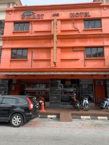 a red hotel with a car parked in front of it at Smart Budget Hotel - Klang in Klang