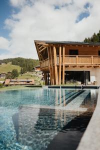 a swimming pool in front of a house at Luxury Spa Chalet Lum d'Or in Selva di Val Gardena