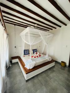 ein Schlafzimmer mit einem weißen Himmelbett in einem Zimmer in der Unterkunft MITI Beach Bungalows in Nungwi