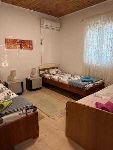 Cette chambre comprend 3 lits et une fenêtre. dans l'établissement Apartman Vesna, à Virpazar