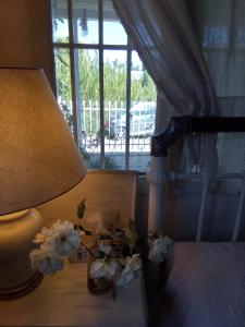 a lamp and flowers on a bed with a window at Marathon agios panteleimon attiki Greece in Panayía Mesosporítissa