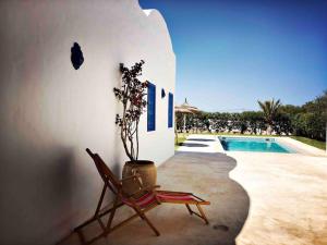 a chair sitting next to a house with a pool at Dar-dina-Total escapism in Djerba in Mezraya