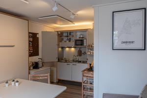 B&B de Drukkerij Zandvoort - luxury private guesthouse في زاندفورت: مطبخ بدولاب بيضاء وطاولة بيضاء