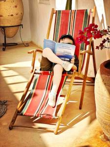a young girl sitting in a rocking chair reading a book at Dar-dina-Total escapism in Djerba in Mezraya