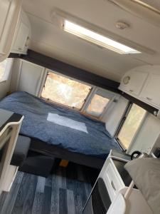 uma vista interior de uma caravana com uma cama e duas janelas em Viršu Glempings em Engure