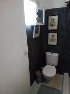 a bathroom with a toilet and pictures on the wall at Marathon agios panteleimon attiki Greece in Panayía Mesosporítissa