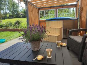 eine Terrasse mit einem Tisch und einer Badewanne im Hinterhof in der Unterkunft Domek nad stawem z banią in Brodnica