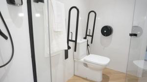 a white bathroom with a toilet and a shower at Hostal León in Torreorgaz