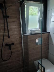 La salle de bains est pourvue d'une douche et d'une fenêtre. dans l'établissement Domek nad stawem z banią, à Brodnica