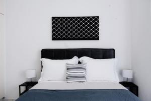 una camera con un letto bianco e nero con due lampade di Joseph Seaside Apartment 2 a Heraklion