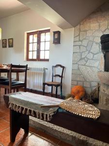 a living room with a table and a stone fireplace at Casa da Pedrada in Ponte da Barca