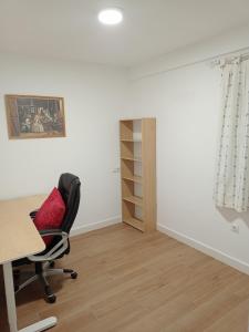 una oficina con escritorio, silla y estante en Apartamento_Santa Isabel en Utrera