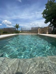 una piscina con acqua blu in un cortile di Molí gran a Santa Eulalia de Ronsaná