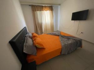 een slaapkamer met een bed met een oranje deken bij Apartamento in Praia