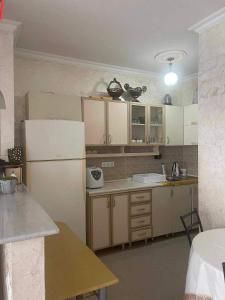 uma cozinha com armários brancos e um frigorífico branco em Batumi house em Salibauri
