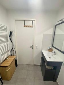 ein weißes Badezimmer mit einem Waschbecken und einem Spiegel in der Unterkunft T2 - Coeur de ville - Bezons in Bezons
