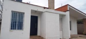 une maison blanche avec une porte bleue et une cheminée dans l'établissement Los niditos, à Salsipuedes
