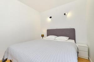 ein Schlafzimmer mit einem weißen Bett mit weißer Bettwäsche in der Unterkunft Apartment Nora in Mali Lošinj