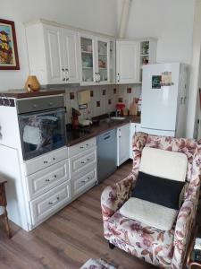 eine Küche mit weißen Schränken, einem Sofa und einem Kühlschrank in der Unterkunft Kod bake u centru in Novi Sad