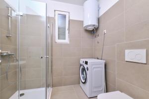 ein Bad mit einer Dusche, einem WC und einer Waschmaschine in der Unterkunft Apartment Nora in Mali Lošinj + 13 Fotos