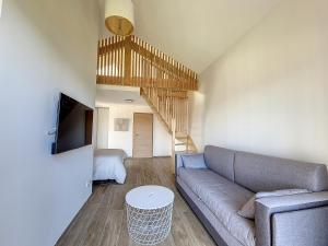 ein Wohnzimmer mit einem Sofa und einer Treppe in der Unterkunft Gîte Le Panoramique in Bilieu