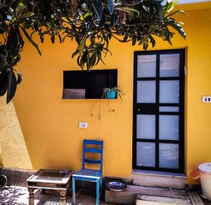 uma cadeira azul sentada em frente a uma parede amarela em Quiet place 3 km from the beach of Cesarea em Or ‘Aqīvāh