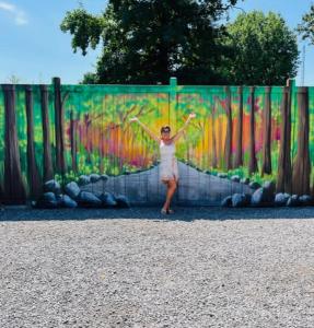 Una mujer parada frente a una valla con los brazos abiertos en Benton Motel, en Benton