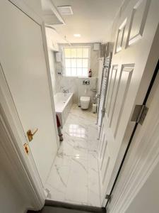 a white bathroom with a toilet and a sink at Entire Apartment hosted by Pius in Redhill