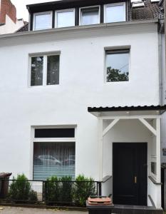 une maison blanche avec une porte noire dans l'établissement Apartment am Diako, à Brême
