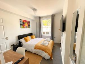 a bedroom with a bed with orange pillows and a television at Entire Apartment hosted by Pius in Redhill