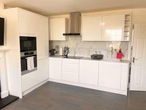 a white kitchen with white cabinets and appliances at Entire Apartment hosted by Pius in Redhill +18 photos