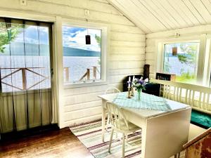 a dining room with a table and a view of the water at Strandgården i Åredalen, stugor in Mörsil