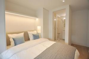 a bedroom with a large white bed with blue pillows at Premium modern flat at Zoute Beach 2 bicylcles included in Knokke-Heist