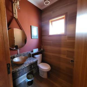 a bathroom with a sink and a toilet and a mirror at Chalé Colorado Vibe in Camanducaia