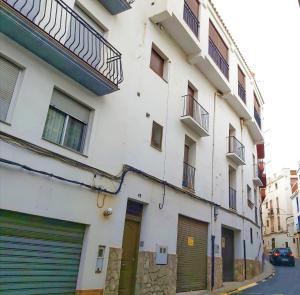 ein weißes Gebäude mit zwei Garagentoren neben einer Straße in der Unterkunft Ca l'Èndula in Lucena del Cid