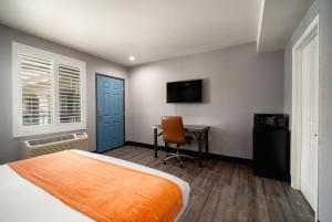 a bedroom with a bed and a desk and a television at LYFE INN & SUITES by AGA - LAX Airport in Inglewood