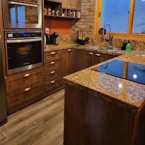 a kitchen with wooden cabinets and granite counter tops at Chalé Colorado Vibe in Camanducaia