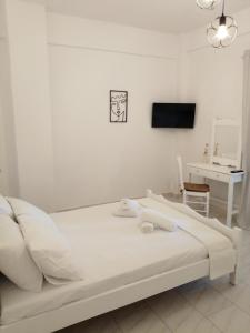 a white bed in a white room with a tv at Pericles Apartment in Dassia