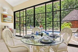 una sala da pranzo con tavolo in vetro e sedie di Spacious 4 Bedroom Villa with Pool, Touring Cart & Maid a Punta Cana