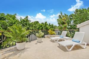 un patio con sedie bianche e piante su un balcone di Spacious 4 Bedroom Villa with Pool, Touring Cart & Maid a Punta Cana