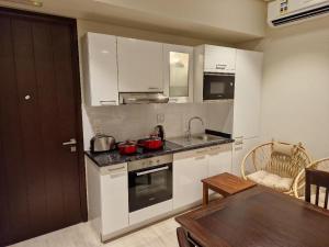 uma cozinha com armários brancos e uma mesa num quarto em Glory Salalah Miko 2 em Salalah