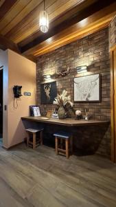 a room with a stone wall with a desk and benches at Chalé Colorado Vibe in Camanducaia
