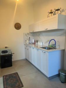 a kitchen with white cabinets and a sink and a stove at נקודות ריפוי in Tirat Karmel