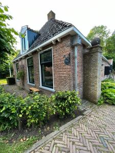 a brick house with a window and a brick sidewalk at Bed and Breakfast Stinzenflora in Cornjum