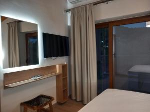 sypialnia z telewizorem, łóżkiem i lustrem w obiekcie BELLΙSIMO3 w mieście Parga