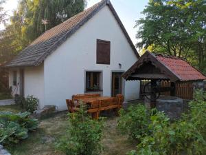 une petite maison blanche avec un banc et une table dans l'établissement Sielski Zakątek, à Srokowo