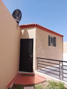 a building with a black door and a gate at Garden Beet in Sidi Rahal