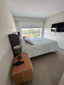 um quarto com uma cama, uma televisão e uma mesa em Torre Green Life FullAmenities em Punta del Este